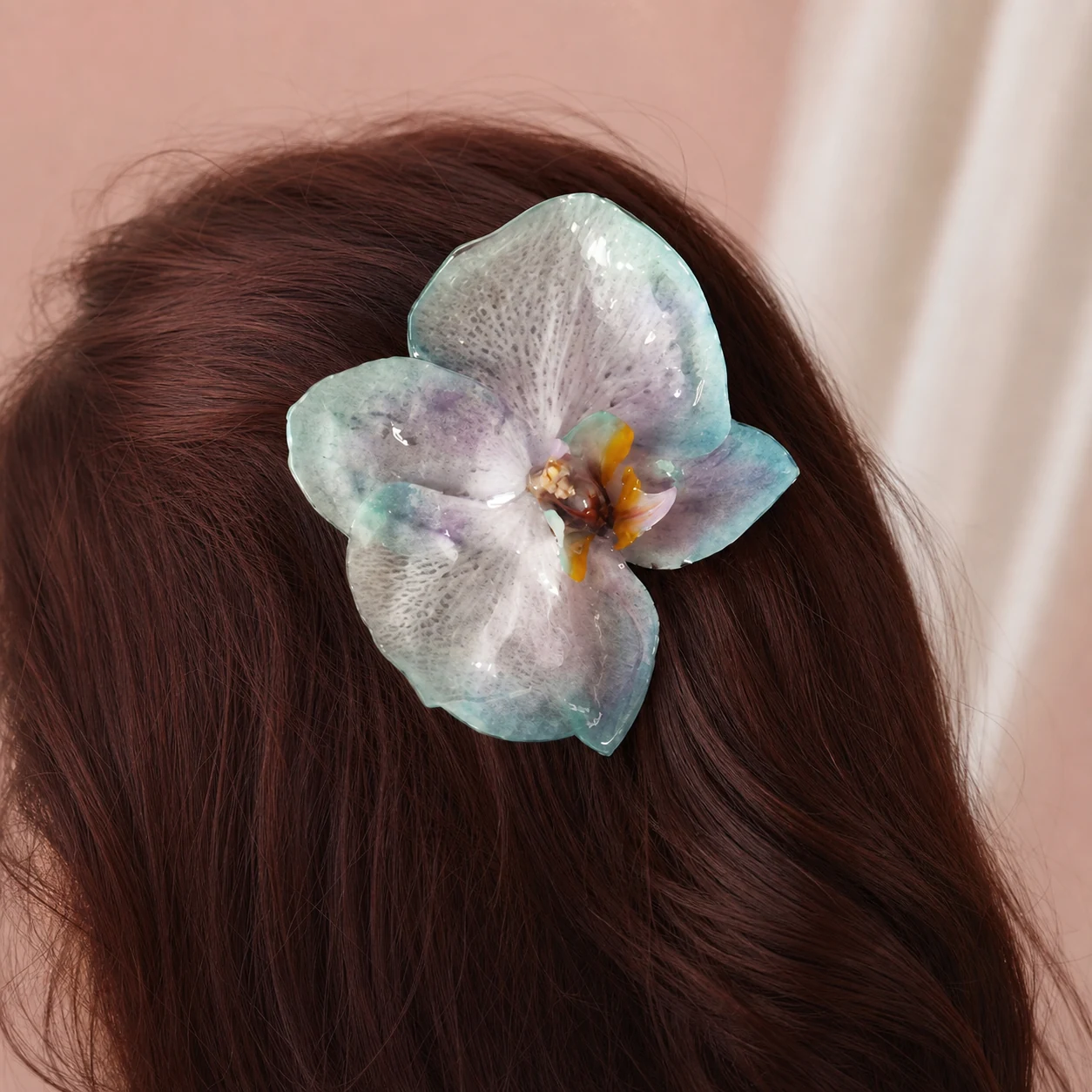 A preserved blue orchid worn in the hair with no face visible