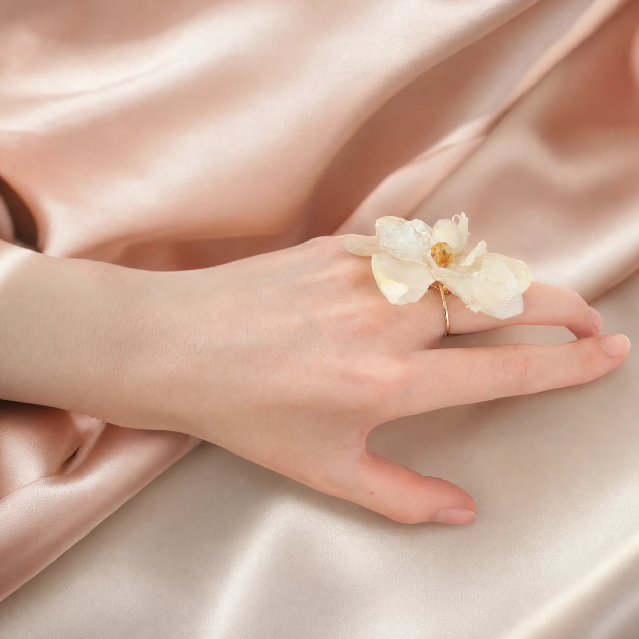 An ivory orchid ring prototype worn on a hand